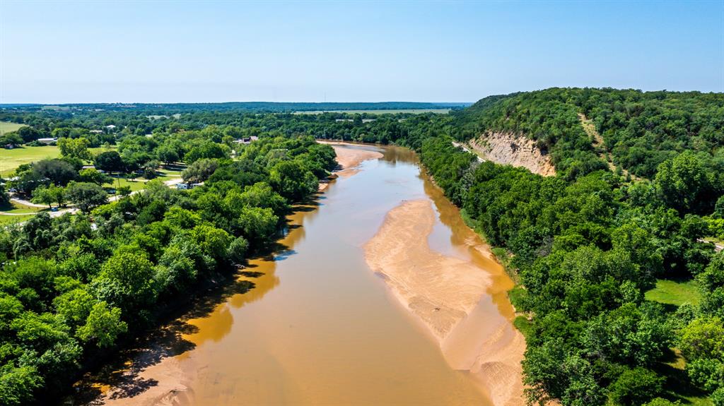 a view of a pathway both side of grassy field with trees