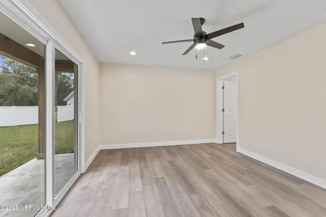 an empty room with wooden floor and a ceiling fan