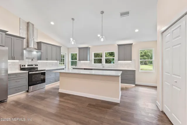 a kitchen with kitchen island granite countertop a stove and a wooden floors