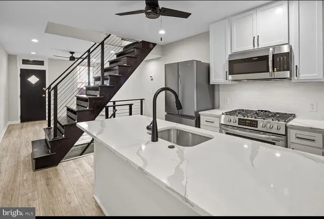 a kitchen with stainless steel appliances kitchen island granite countertop a sink a stove and cabinets