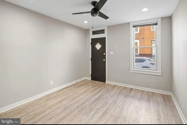a view of an empty room with a window and wooden floor