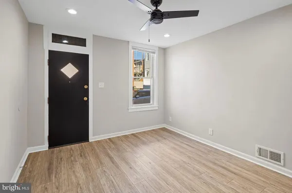 a view of an empty room with wooden floor and a ceiling fan