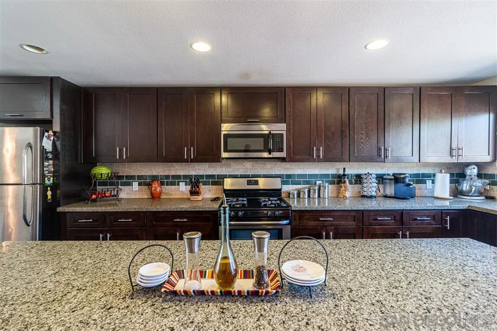 8648 Almond Road Lakeside, CA 92040 - Photo 6 of 15 a kitchen with a stove a microwave a sink and cabinets