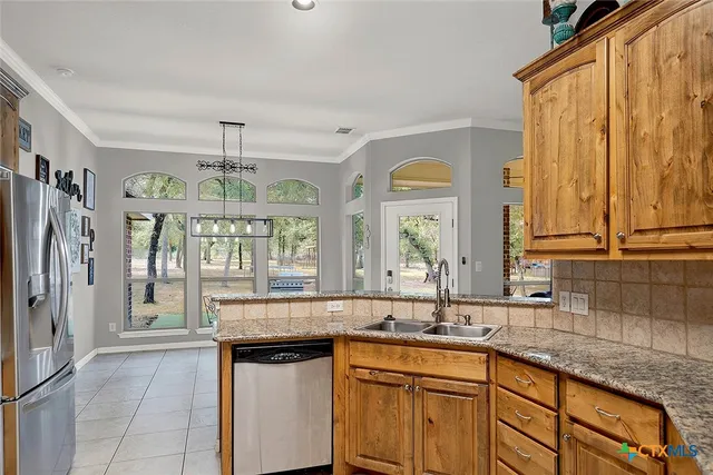 a kitchen with stainless steel appliances granite countertop a sink and a refrigerator