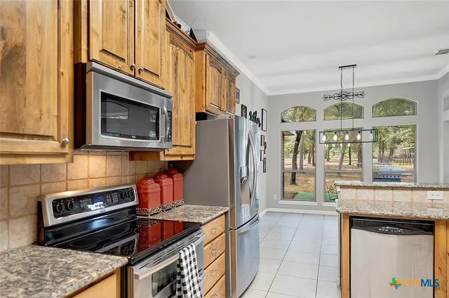 a kitchen with stainless steel appliances granite countertop a refrigerator and a stove top oven