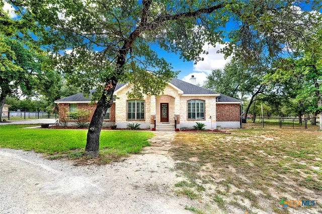 a front view of a house with a garden and trees