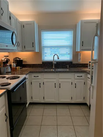 a kitchen with granite countertop a sink a stove and cabinets