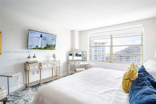 a spacious bedroom with a bed and a flat screen tv