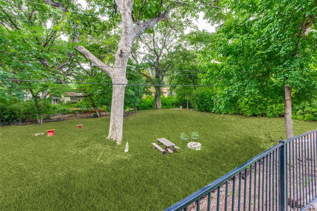 4316 Springbranch Drive Benbrook, TX 76116 - Photo 33 of 39 Expansive backyard featuring mature trees, a manicured lawn, and a black wrought iron fence
