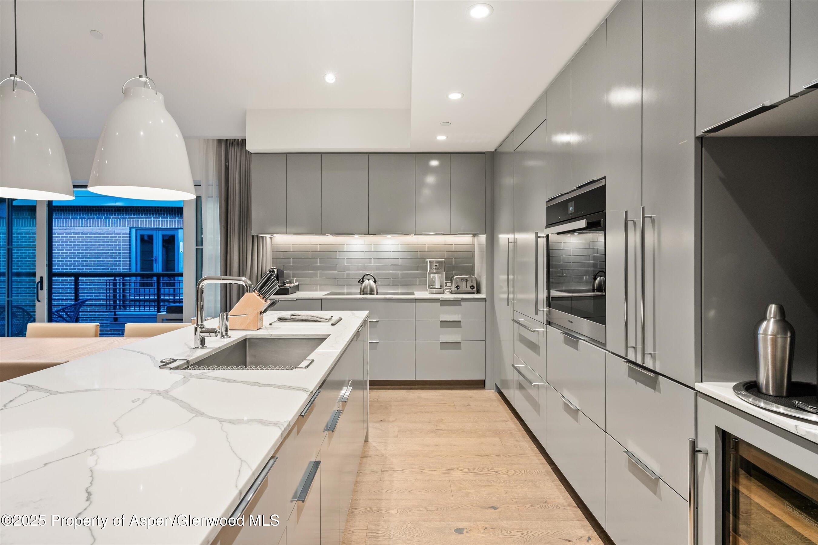 550 South Spring Street, Unit F10 110 Aspen, CO 81611 - Photo 18 of 58 a kitchen with stainless steel appliances kitchen island granite countertop a refrigerator and a sink