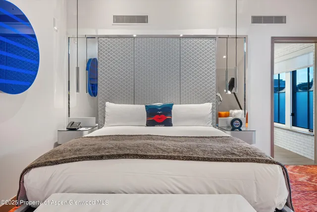 a bedroom with a bed and a lamp on dresser