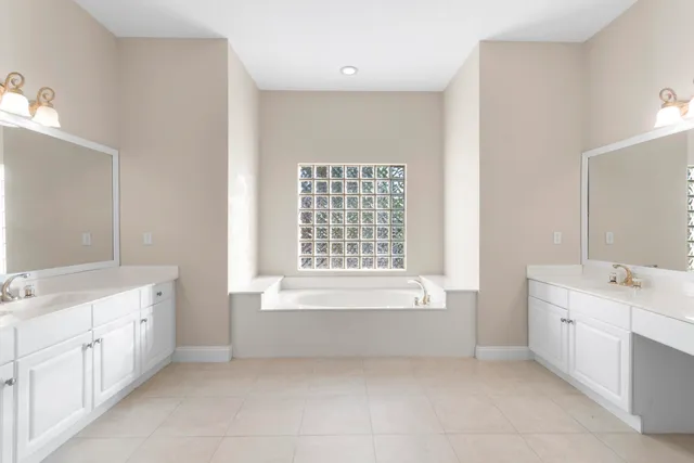 a bathroom with a bathtub sink double vanity and mirror