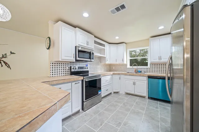 a kitchen with granite countertop a sink a counter top space appliances and cabinets