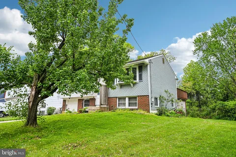 a front view of a house with a garden and trees