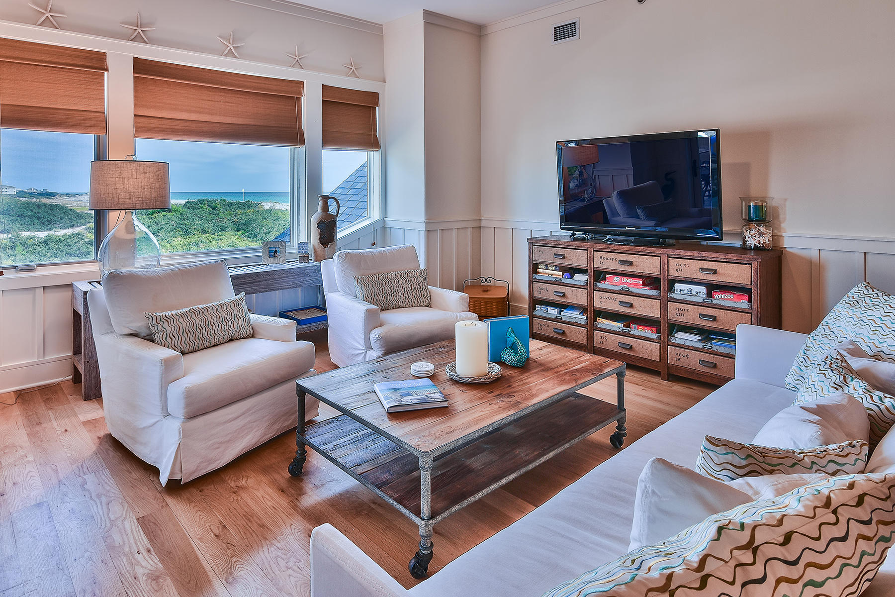 99 Compass Point Way, Unit 303 Watersound, FL 32461 - Photo 1 of 24 a living room with furniture a flat screen tv and a floor to ceiling window