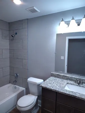a bathroom with a granite countertop sink a toilet and bathtub