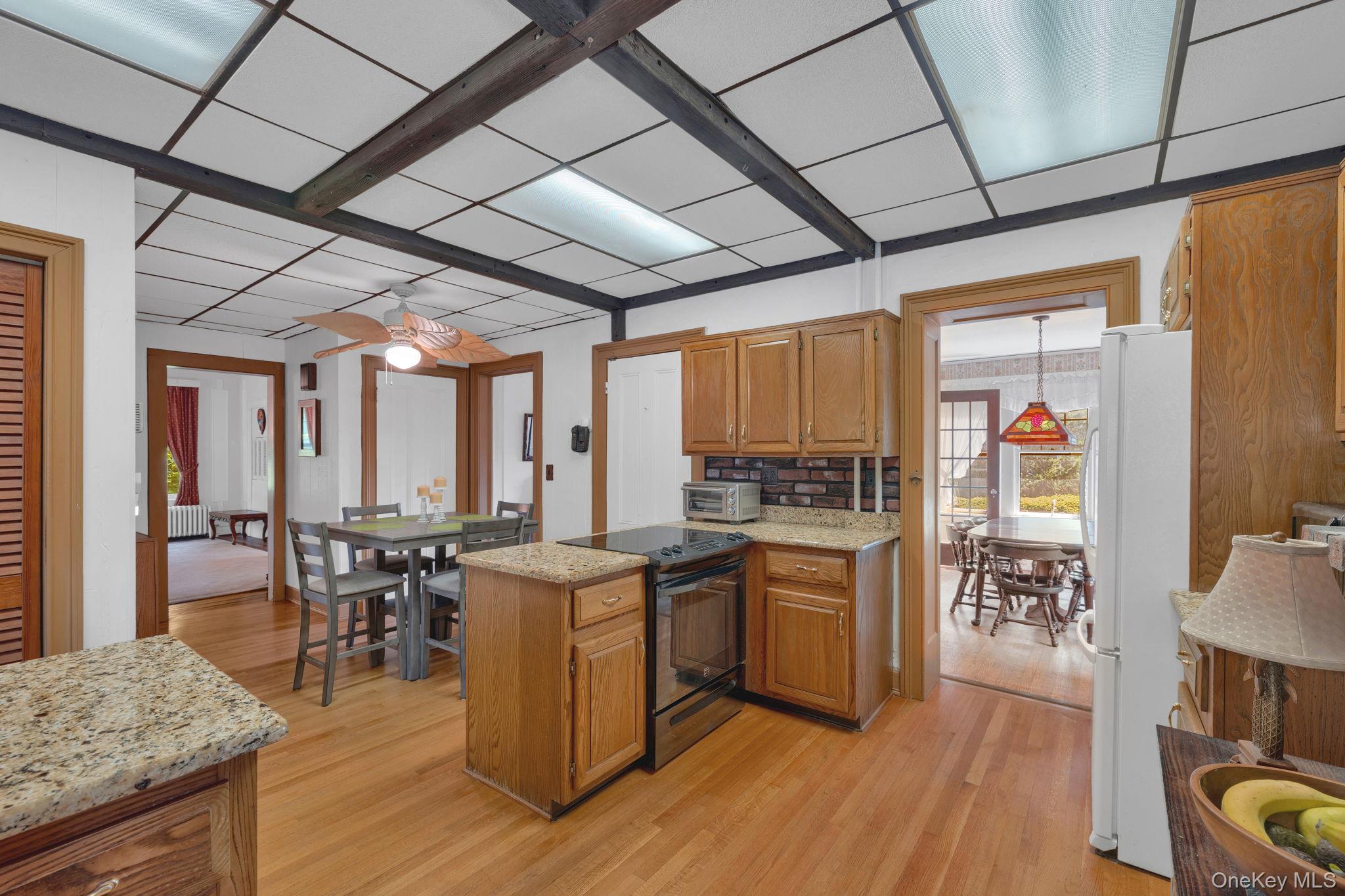 470 Little Britain Road Newburgh, NY 12550 - Photo 23 of 45 Kitchen with black range oven, light wood-style flooring, brown cabinetry, light stone counters, and freestanding refrigerator