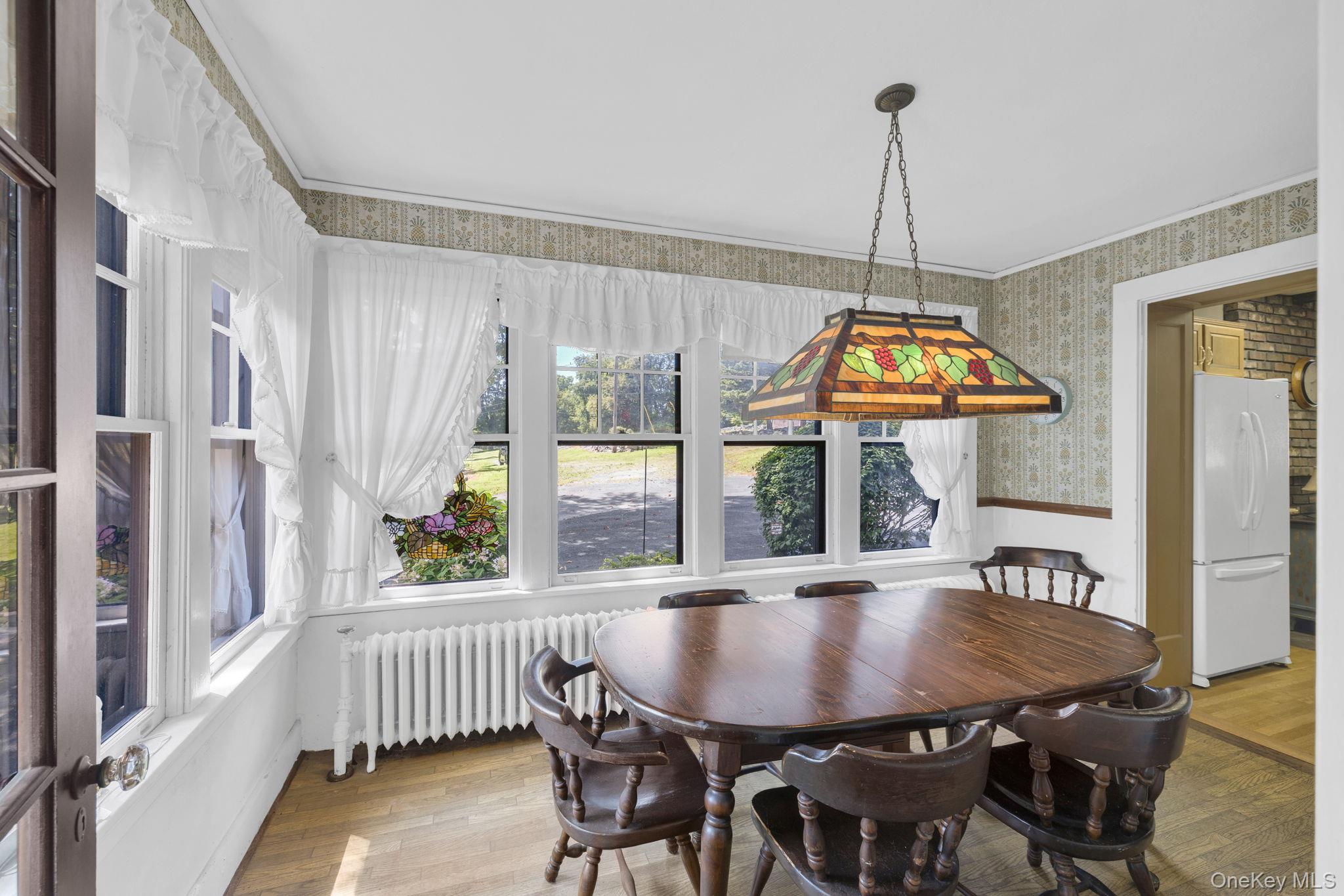 470 Little Britain Road Newburgh, NY 12550 - Photo 25 of 45 Dining room featuring radiator heating unit, light wood-type flooring, wallpapered walls, crown molding, and a wainscoted wall