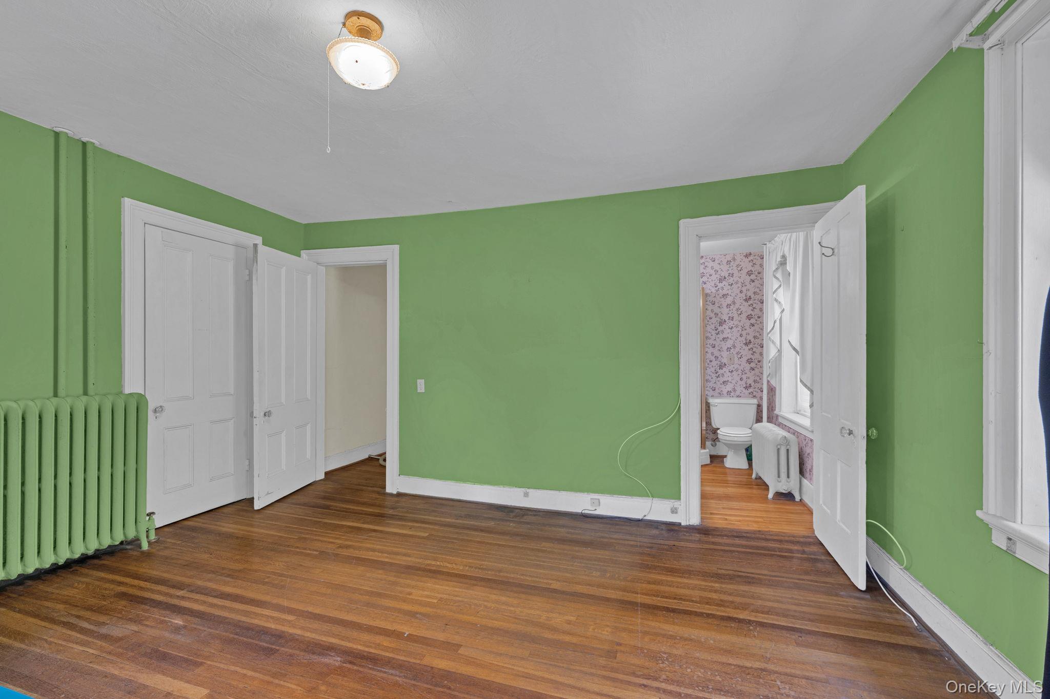 470 Little Britain Road Newburgh, NY 12550 - Photo 30 of 45 Unfurnished bedroom with radiator heating unit, dark wood-style floors, and ensuite bathroom
