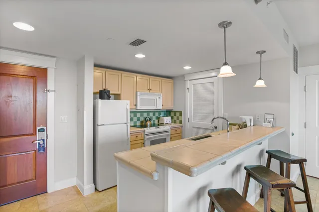 a kitchen with kitchen island a refrigerator a stove a dining table and chairs with wooden floor