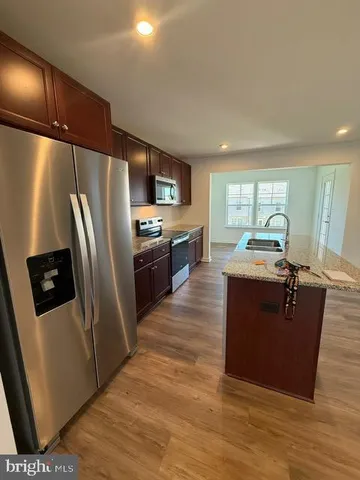 a kitchen with granite countertop a refrigerator stove and sink