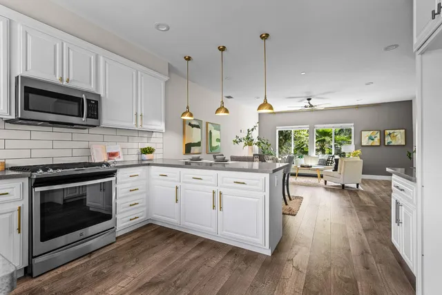 a kitchen with kitchen island granite countertop a stove a sink a oven a dining table and chairs with wooden floor