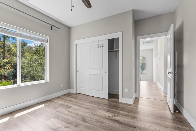 a view of empty room with wooden floor and fan