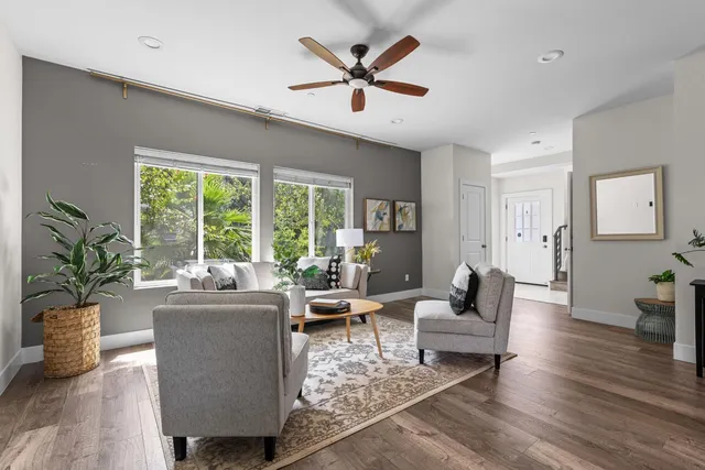 a living room with furniture ceiling fan and a large window
