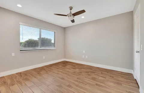 a view of empty room with wooden floor and fan