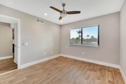 a view of empty room with wooden floor and ceiling fan