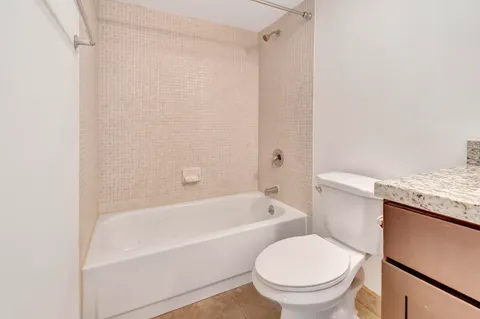 a bathroom with a granite countertop bathtub shower sink vanity and toilet