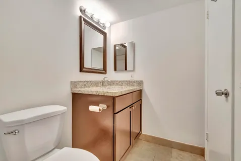 a bathroom with a granite countertop toilet sink and mirror
