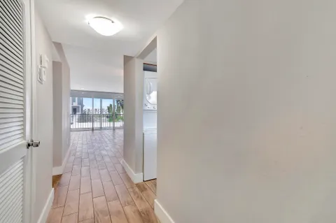 a view of a hallway with wooden floor and a bathroom