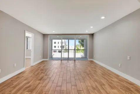 a view of an empty room with wooden floor and a window