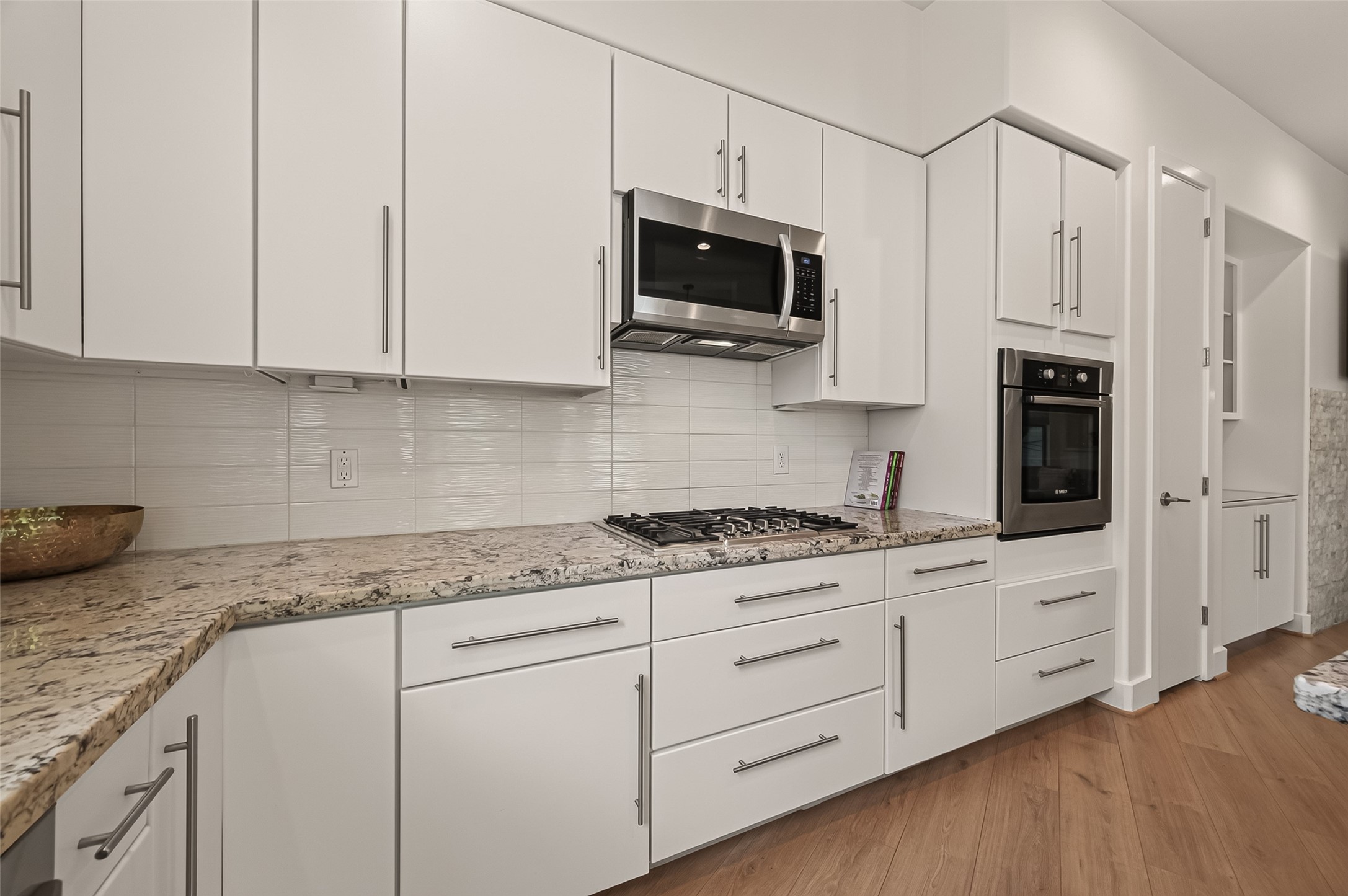 1767 Michigan Street Houston, TX 77006 - Photo 10 of 33 Modern kitchen featuring sleek white cabinetry, granite countertops, stainless steel appliances, and a built-in oven. The space is bright and spacious with clean lines and a contemporary design.