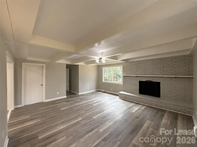 an empty room with windows and fireplace