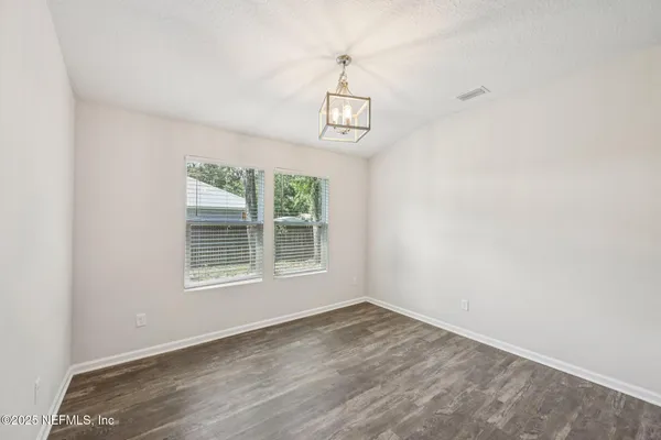 an empty room with wooden floor ceiling fan and windows