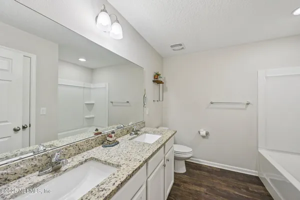 a bathroom with a granite countertop sink a toilet and shower