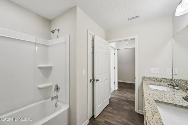 a bathroom with a granite countertop sink a mirror bathtub and shower