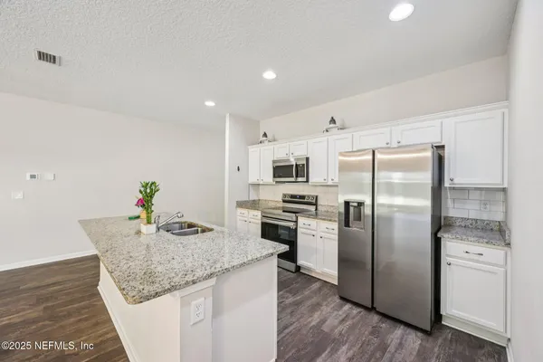 a kitchen with stainless steel appliances granite countertop a refrigerator a stove a sink a microwave and island