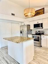512 Wideview Avenue Tarpon Springs, FL 34689 - Photo 7 of 30 a kitchen with stainless steel appliances granite countertop a sink a stove top oven a counter space and cabinets