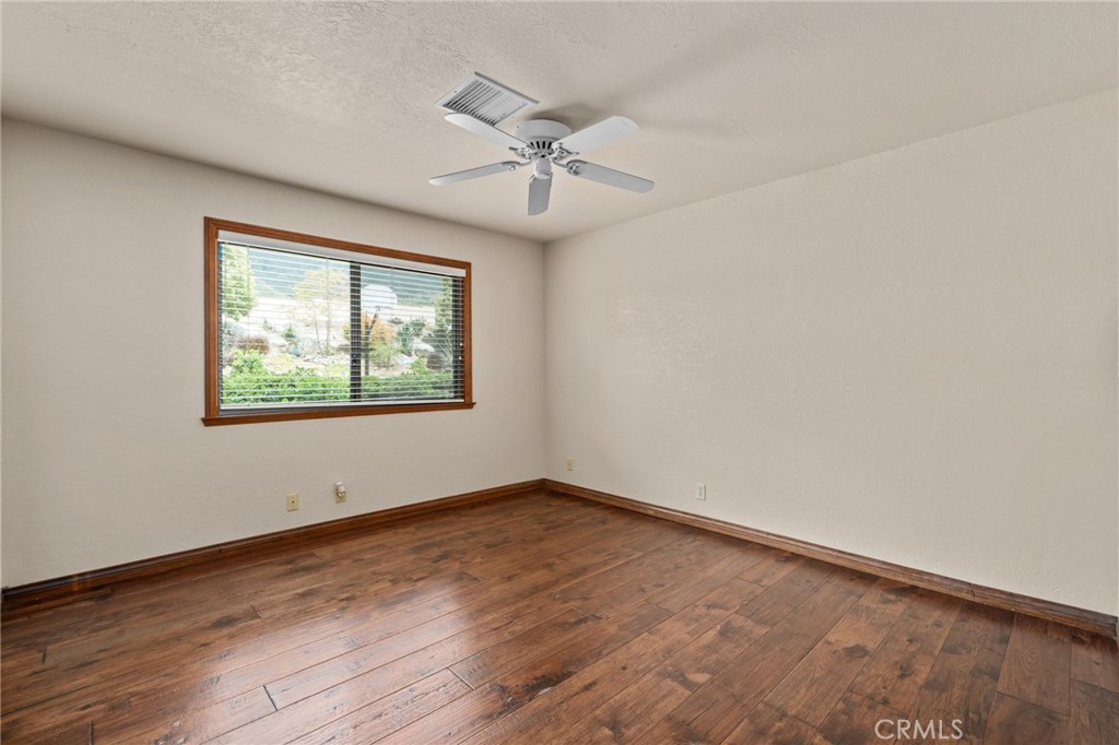 5297 Amethyst Street Rancho Cucamonga, CA 91737 - Photo 33 of 64 an empty room with wooden floor chandelier fan and windows
