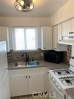 a kitchen with kitchen island granite countertop a sink a stove and cabinets