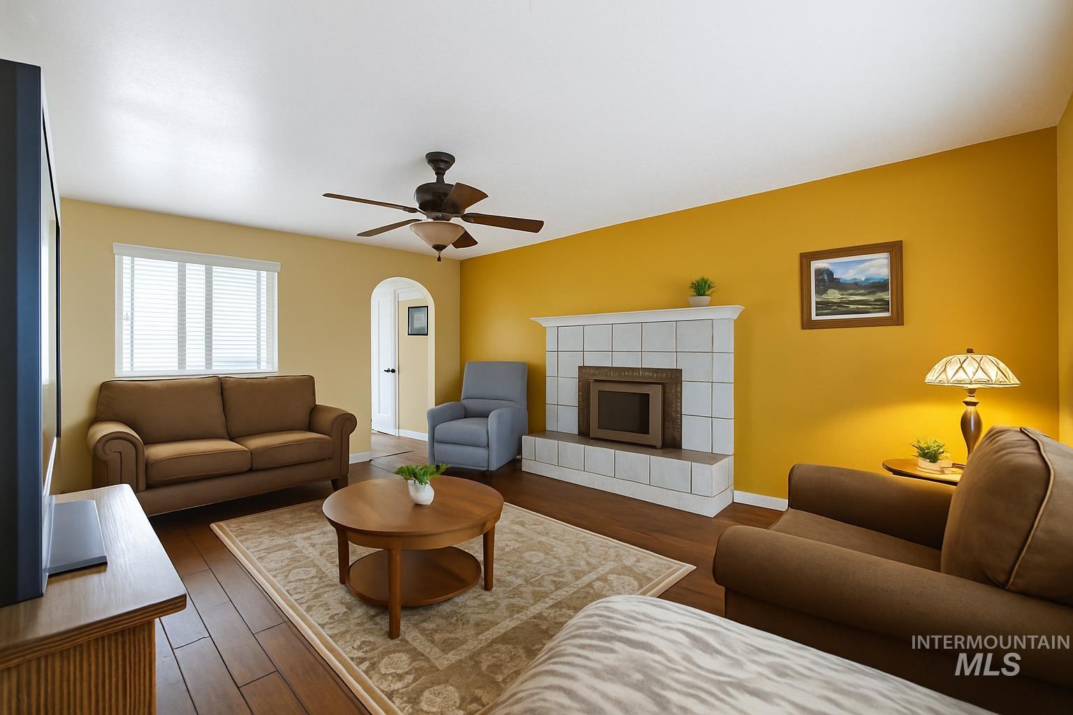173 Fafnir Drive Kimberly, ID 83341 - Photo 13 of 42 Living area with ceiling fan, a tiled fireplace, dark wood-style flooring, and arched walkways