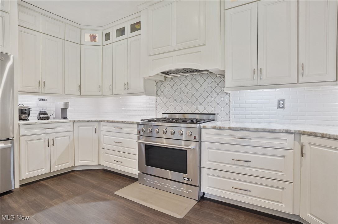 7305 Alexander Road Painesville, OH 44077 - Photo 26 of 50 Kitchen with extra large 6 burner chef stove, granite counters, white cabinets, lvt flooring, and decorative backsplash