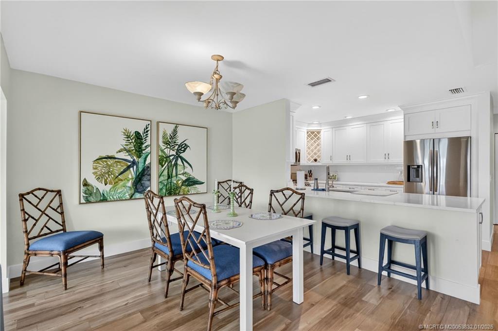 5627 Southeast Foxcross Place Stuart, FL 34997 - Photo 17 of 72 a view of a dining room with furniture wooden floor and a chandelier