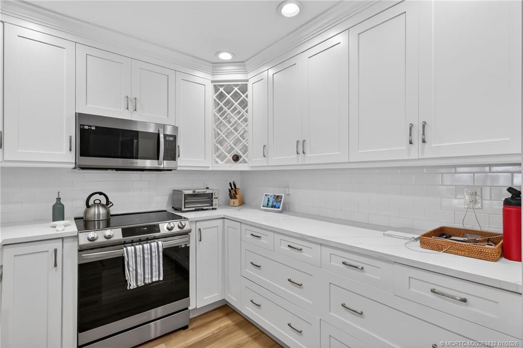 5627 Southeast Foxcross Place Stuart, FL 34997 - Photo 21 of 72 a kitchen with white cabinets and stainless steel appliances