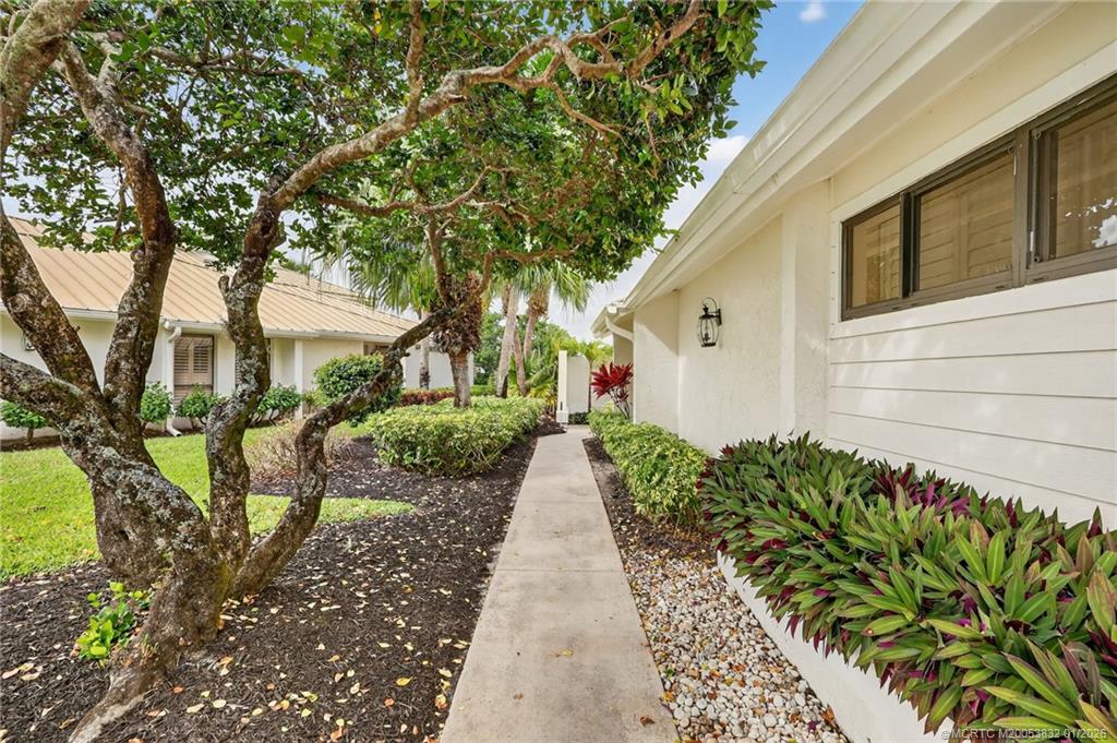 5627 Southeast Foxcross Place Stuart, FL 34997 - Photo 4 of 72 a view of a pathway with a white house next to a yard