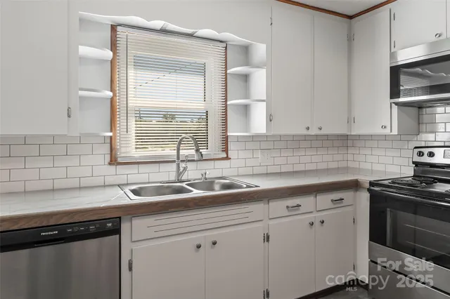 a kitchen with stainless steel appliances granite countertop a sink a stove and dishwasher next to a window