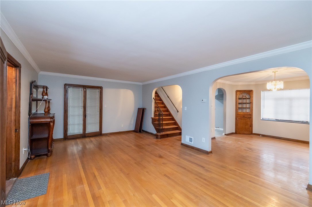 4668 Broadale Road Cleveland, OH 44109 - Photo 12 of 25 Unfurnished living room featuring light hardwood / wood-style flooring, ornamental molding, and a notable chandelier